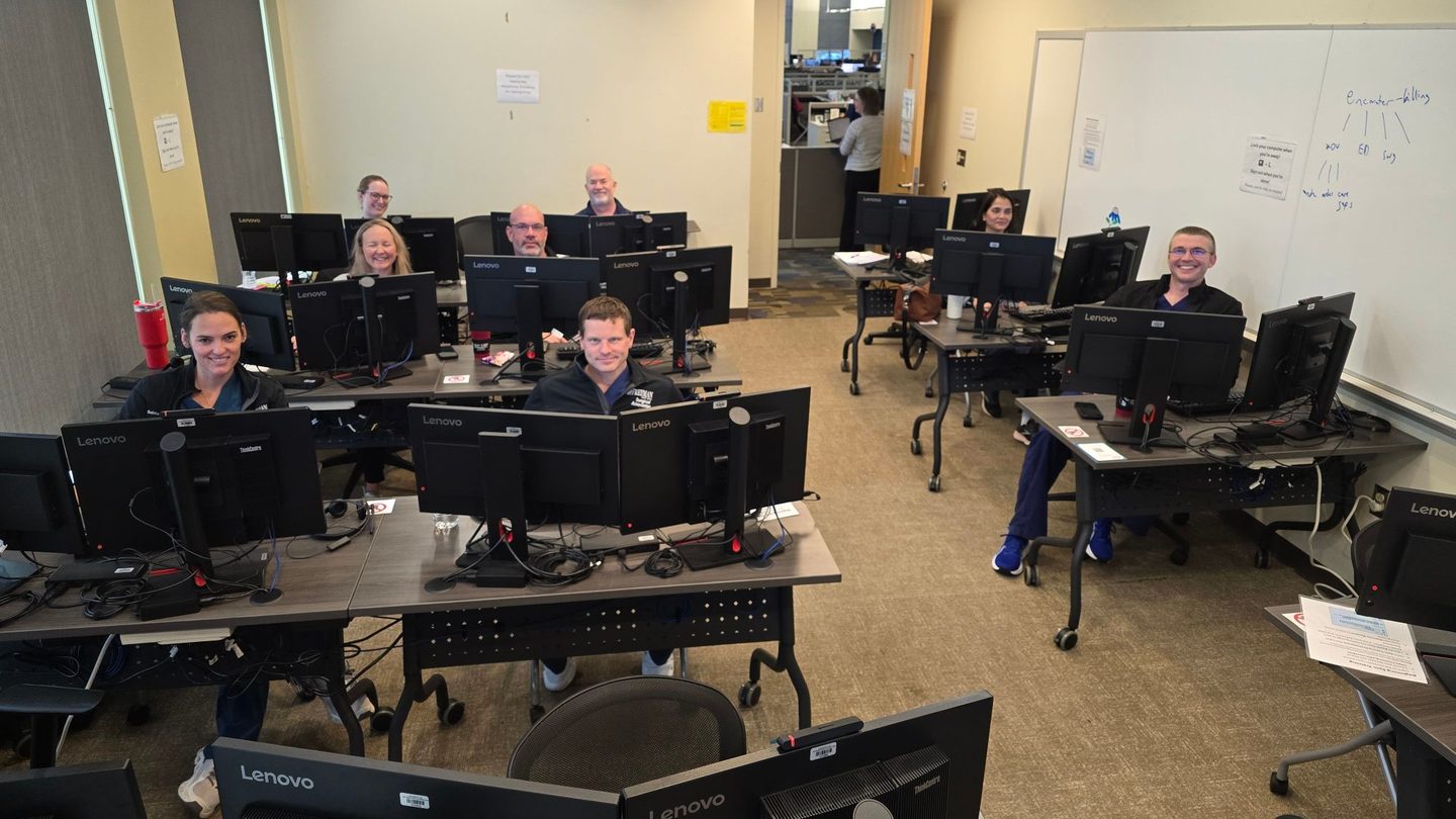 Trauma surgery providers smiling at their workstations during an Epic training class